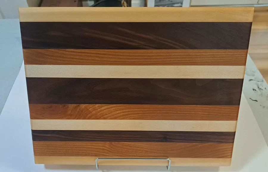 Walnut, cherry and maple striped cutting board on a stand